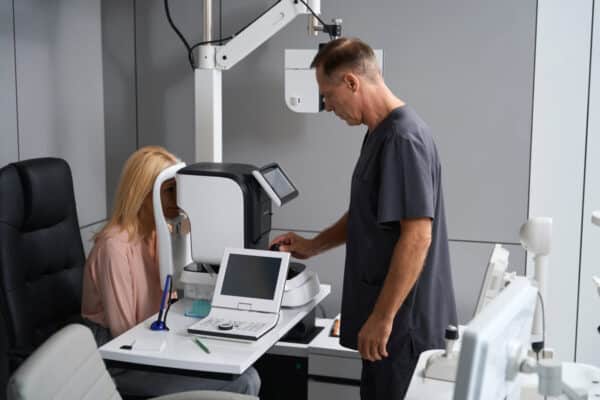 Osoba poddaje się optometrycznemu badaniu wzroku przy pomocy specjalistycznego urządzenia.