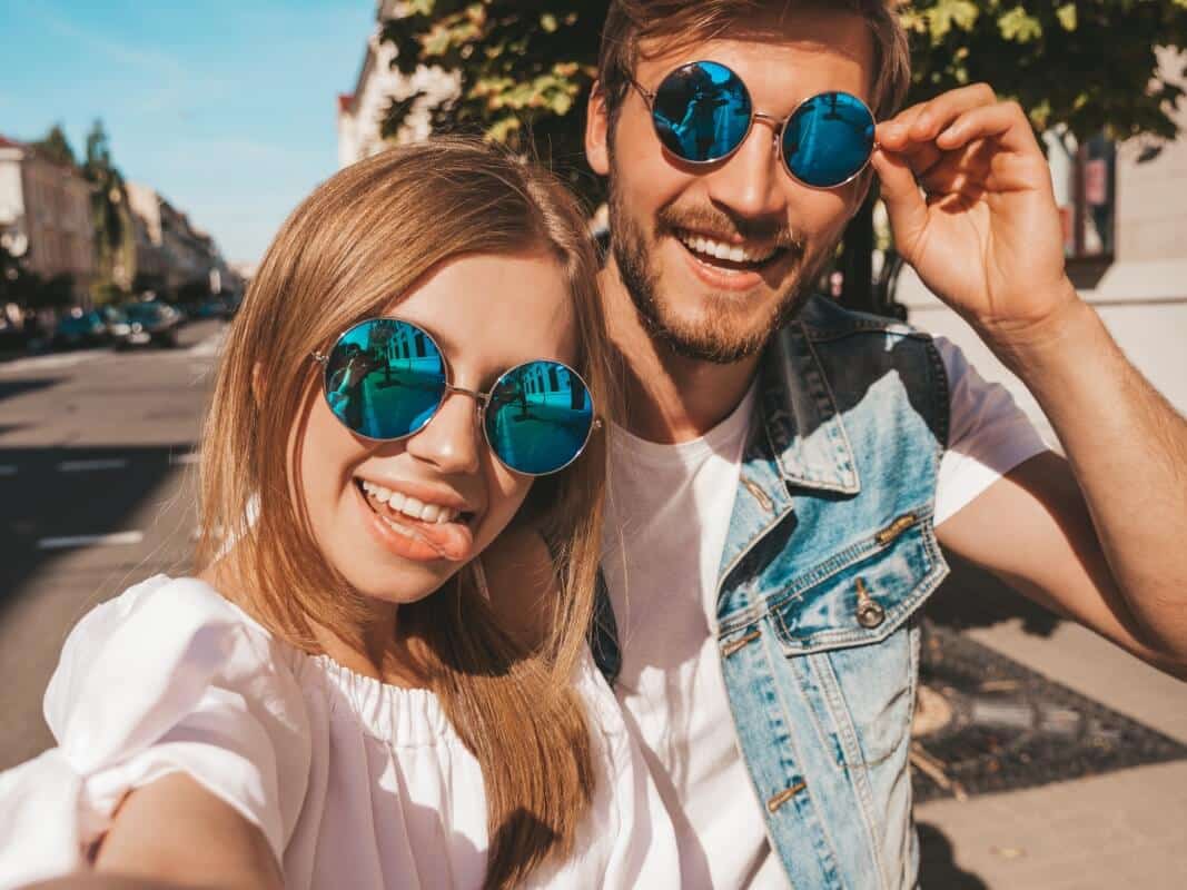 Para uśmiecha się w słońcu, nosząc modne okulary przeciwsłoneczne.