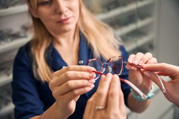 Kobieta trzyma okulary i przygląda się oprawkom.