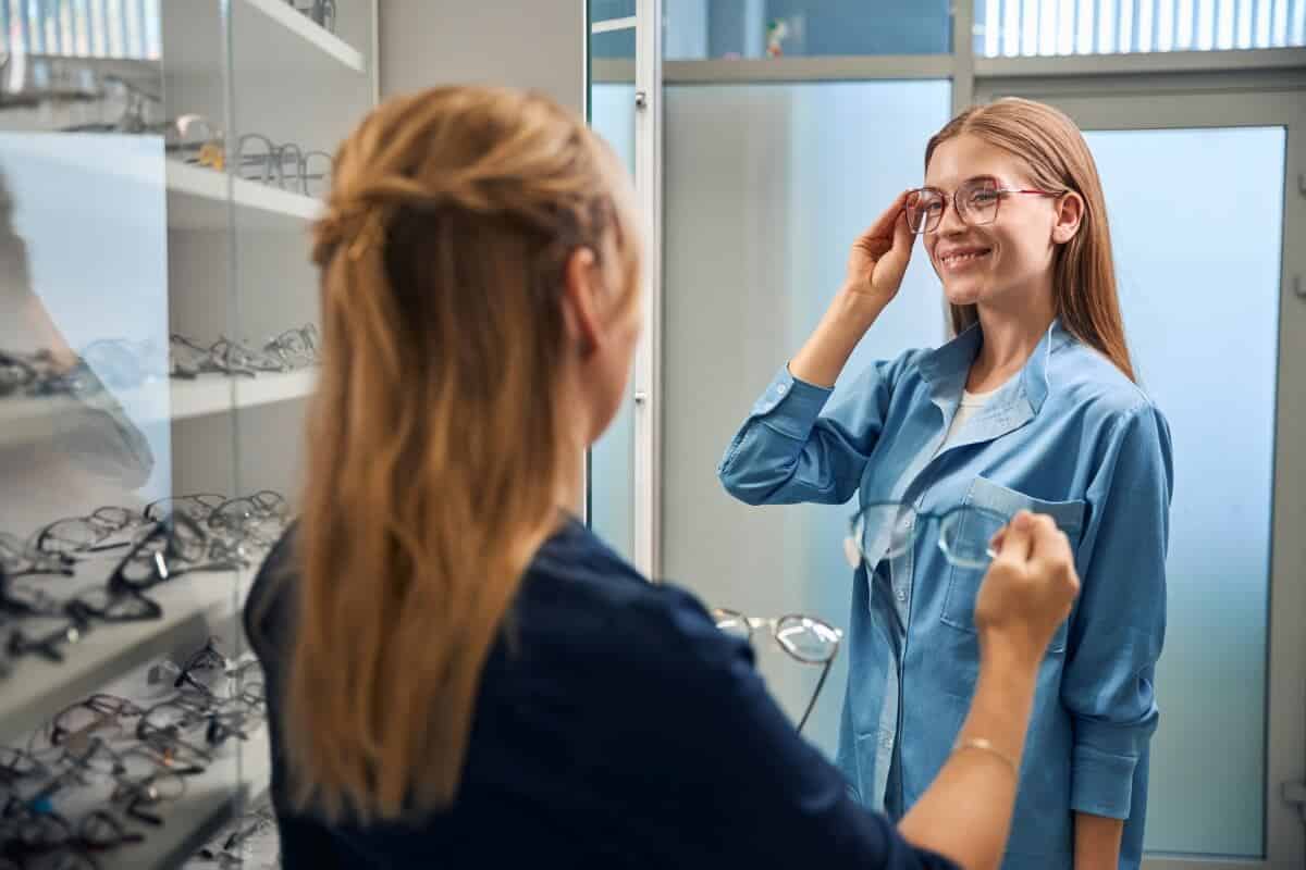 Kobieta przymierza okulary progresywne w sklepie optycznym.