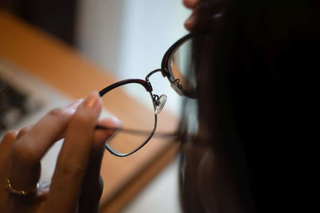 Osoba trzyma szkła okularowe w dłoniach.