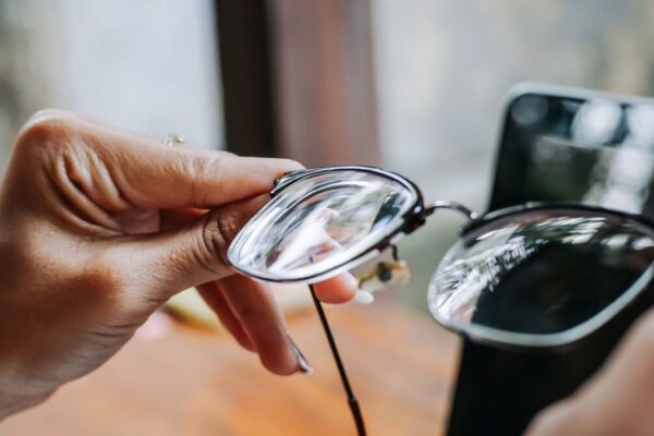 Ręka trzymająca okulary z przejrzystymi szkłami okularowymi.