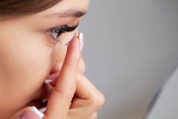 Osoba zakłada soczewki kontaktowe na oko.