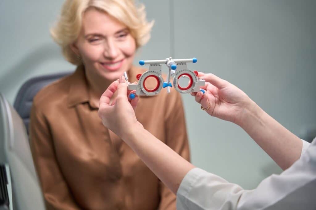 Kobieta uśmiecha się podczas badania wzroku u optometrysty.