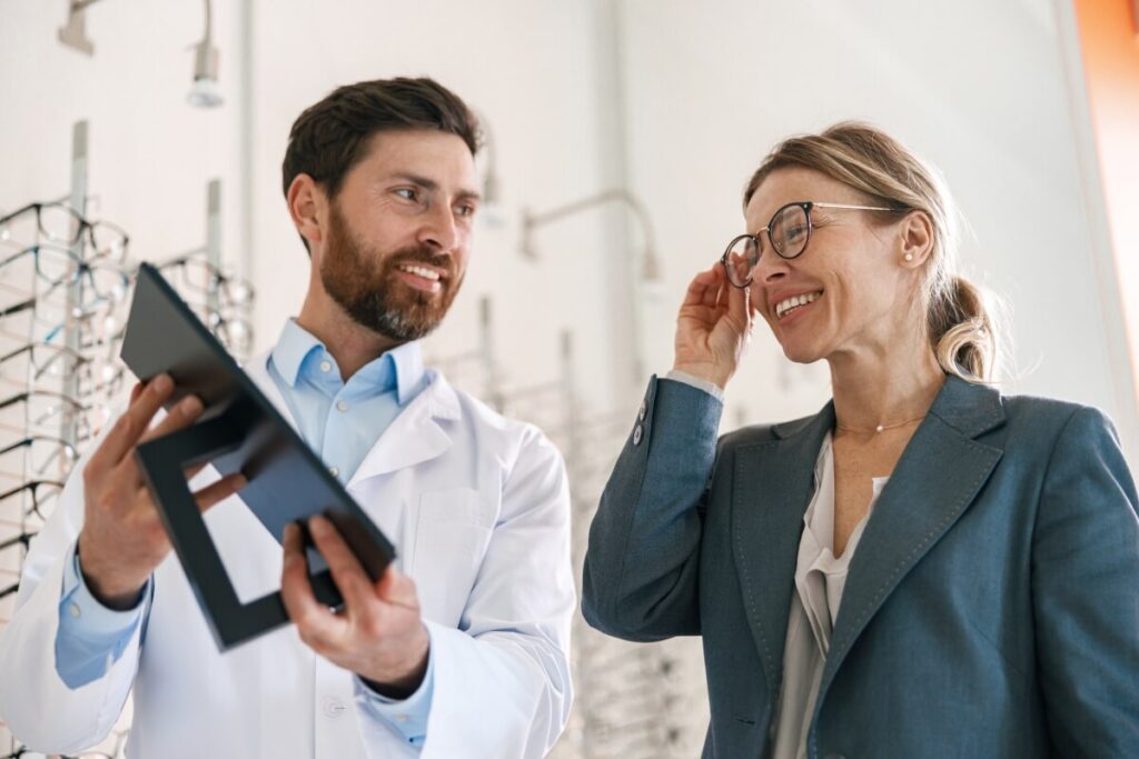Optometrysta pomaga kobiecie wybrać oprawki okularowe.