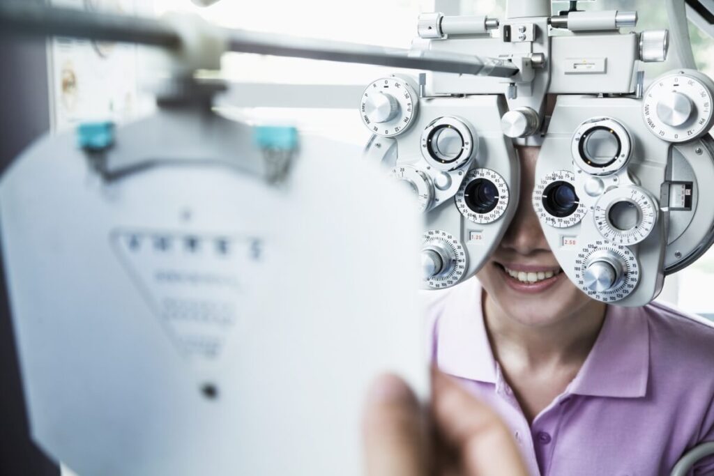 Osoba przechodzi badanie wzroku u optometrysty przy użyciu foroptera.