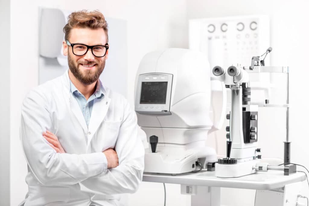 Optometrysta stojący w gabinecie przy sprzęcie do badania wzroku.